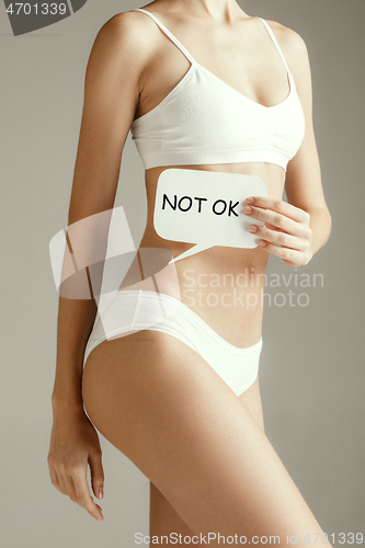 Image of Young adult woman holding paper card for sign or symbol.