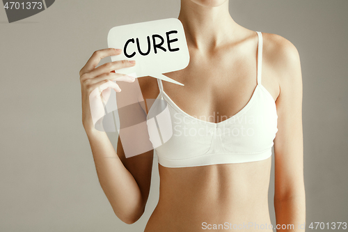 Image of Woman health. Female model holding card near breast