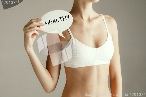 Image of Young adult woman holding paper card with word HEALTHY.