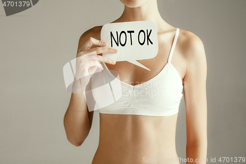 Image of Woman health. Female model holding card near breast