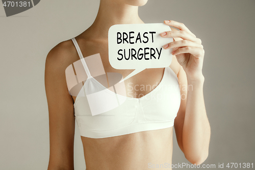 Image of Woman health. Female model holding card near breast