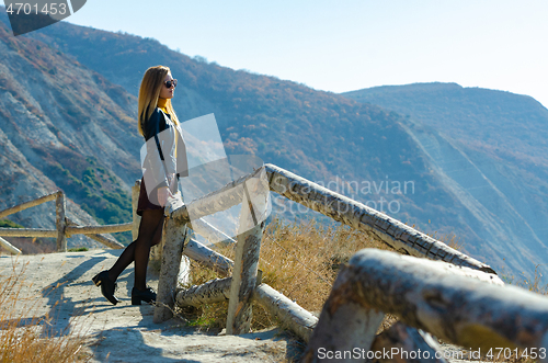 Image of A girl on a sunny warm day watches a beautiful view from the mountain