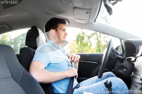 Image of man or car driver fastening seat belt