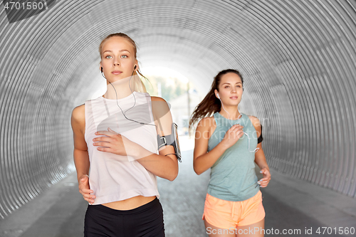 Image of young women with earphones and smartphones running