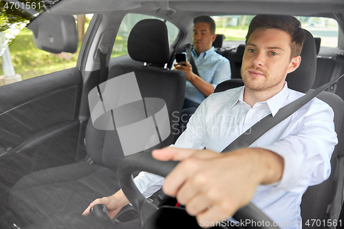 Image of male taxi driver driving car with passenger