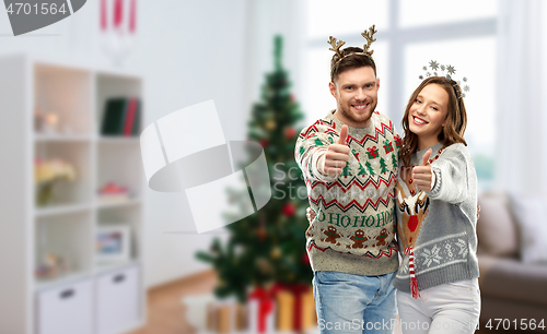 Image of couple in christmas ugly sweaters shows thumbs up