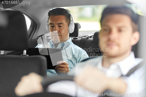 Image of man with tablet pc and headphones riding in car