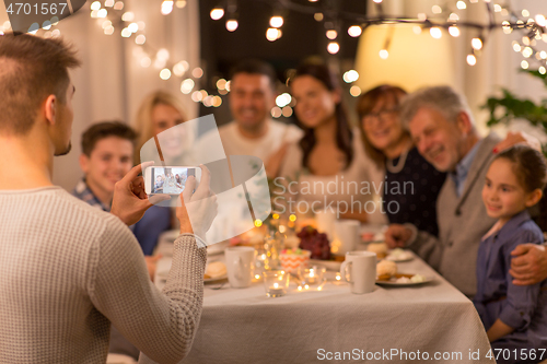 Image of man taking picture of family at dinner party