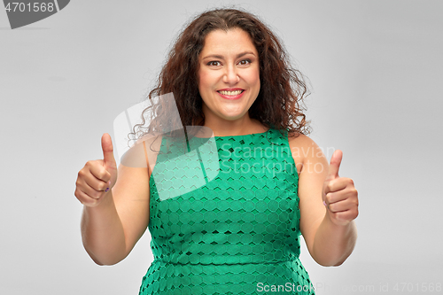 Image of happy woman in green dress showing thumbs up