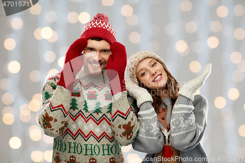 Image of couple in ugly sweaters and mittens on christmas