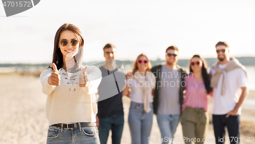 Image of woman with friends on beach showing thumbs up