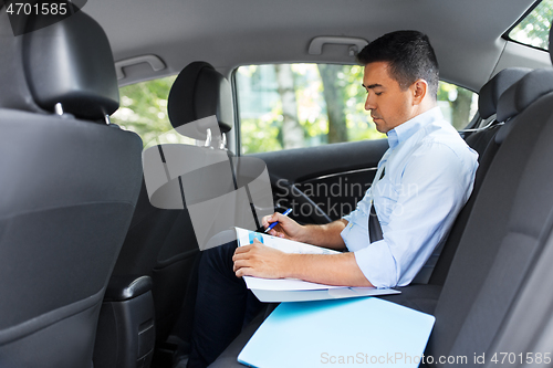 Image of businessman with coffee on car back seat