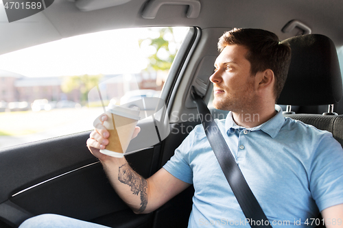 Image of man with takeaway coffee on back seat of taxi car