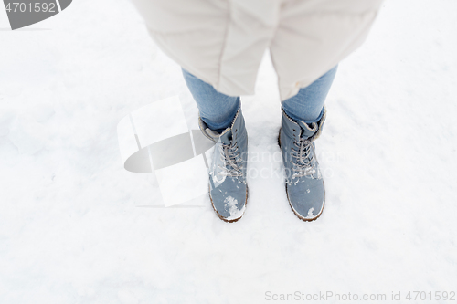 Image of female feet in winter shoes on snow from top