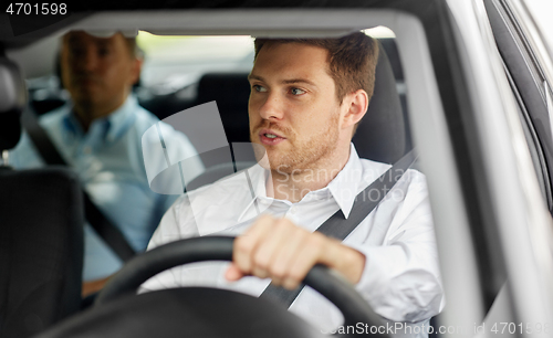 Image of male driver driving car with passenger