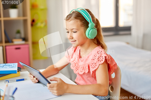 Image of girl in headphones with tablet computer at home