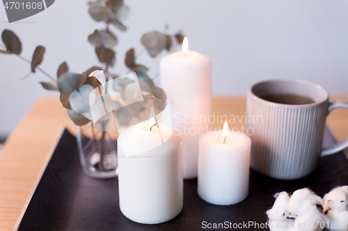 Image of candles, tea and branches of eucalyptus on table