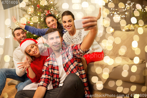 Image of friends celebrating christmas and taking selfie