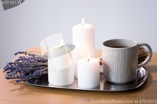 Image of candles, tea in mug and lavender flowers on table