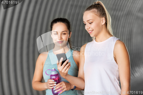 Image of women or female friends with smartphone and flask