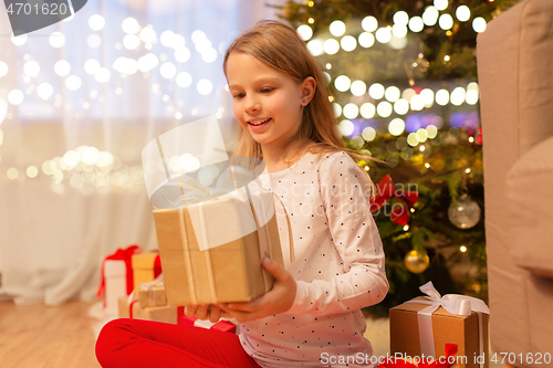 Image of smiling girl with christmas gift at home