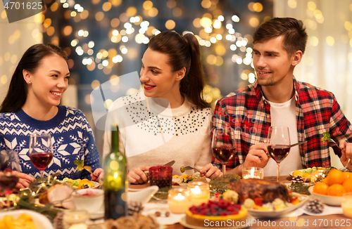 Image of happy friends having christmas dinner at home