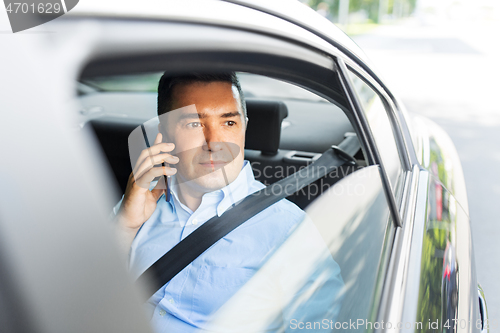 Image of male passenger calling on smartphone in taxi car