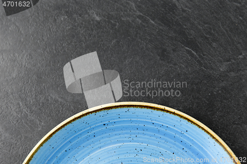 Image of close up of blue ceramic plate on slate background