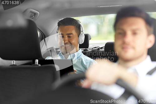 Image of man with tablet pc and headphones riding in car