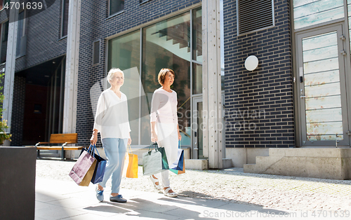 Image of senior women with shopping bags walking in city