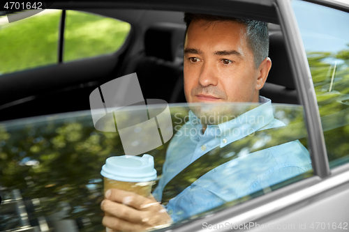 Image of man drinking takeaway coffee on car back seat