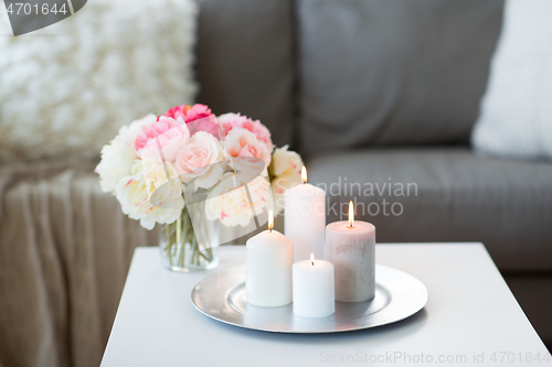 Image of candles burning on table and flowers at cozy home