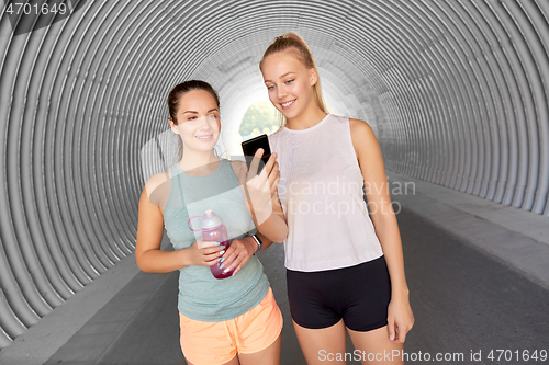 Image of women or female friends with smartphone and flask