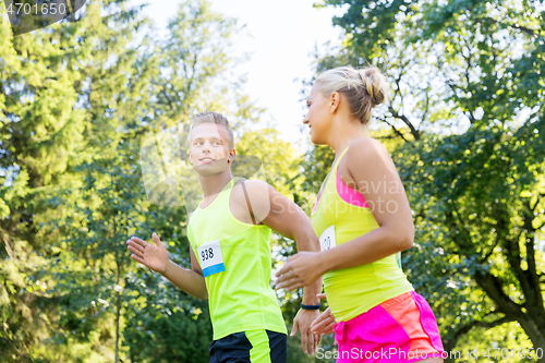 Image of happy couple of sportsmen racing wit badge numbers