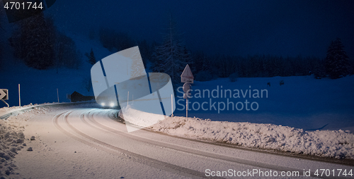 Image of car driving on dangerous road at night on snow