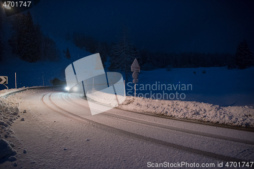 Image of car driving on dangerous road at night on snow