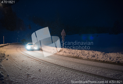 Image of car driving on dangerous road at night on snow