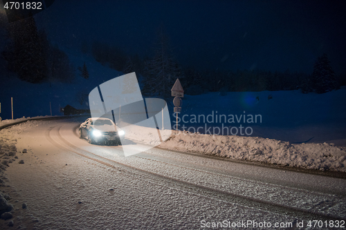 Image of car driving on dangerous road at night on snow