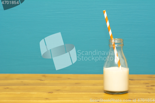 Image of Glass milk bottle half full with a retro paper straw
