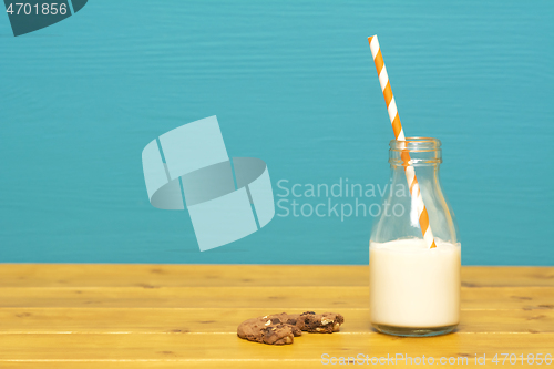 Image of Straw and half full milk bottle with a half-eaten cookie