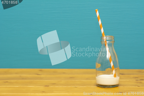 Image of Glass bottle with dregs of milk with a paper straw