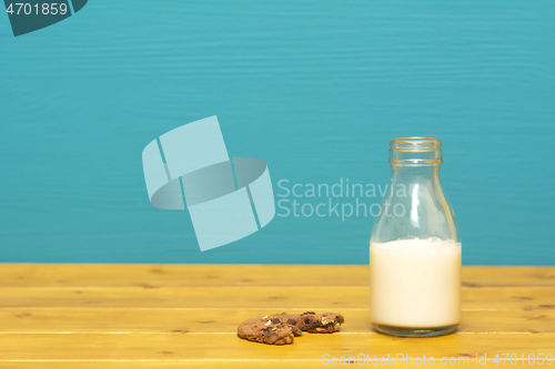 Image of Half full milk bottle and a half-eaten chocolate cookie