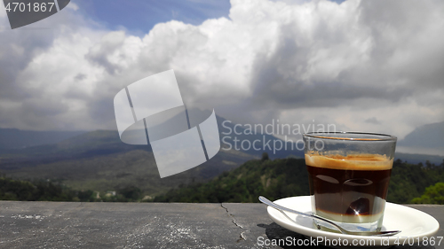 Image of Mug with hot coffee with background of Batur volcano and lake