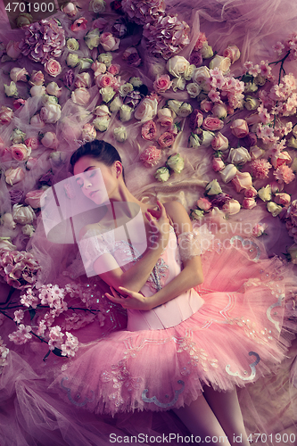 Image of Young woman in pink ballet tutu surrounded by flowers