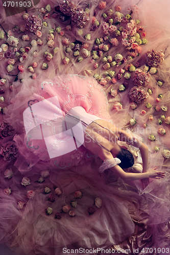 Image of Young woman in pink ballet tutu surrounded by flowers