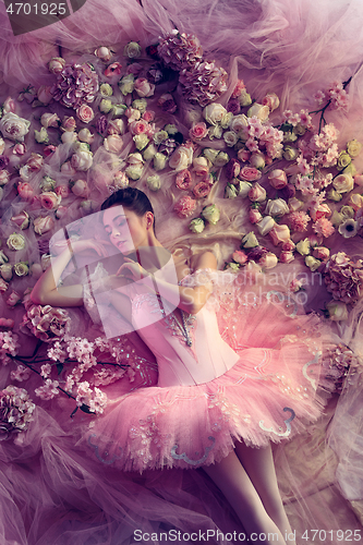 Image of Young woman in pink ballet tutu surrounded by flowers