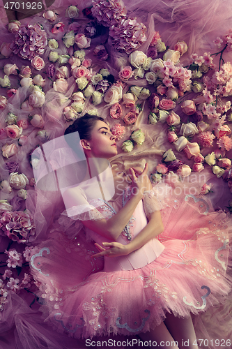 Image of Young woman in pink ballet tutu surrounded by flowers