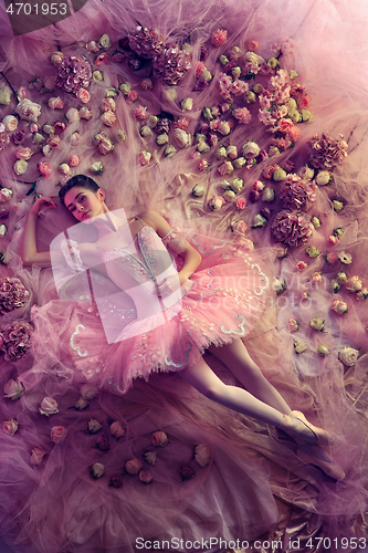 Image of Young woman in pink ballet tutu surrounded by flowers