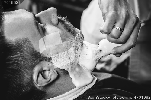 Image of Client during beard shaving at barbershop.