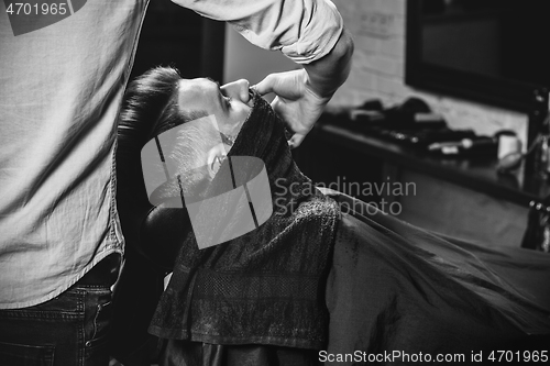 Image of Client during beard shaving at barbershop.